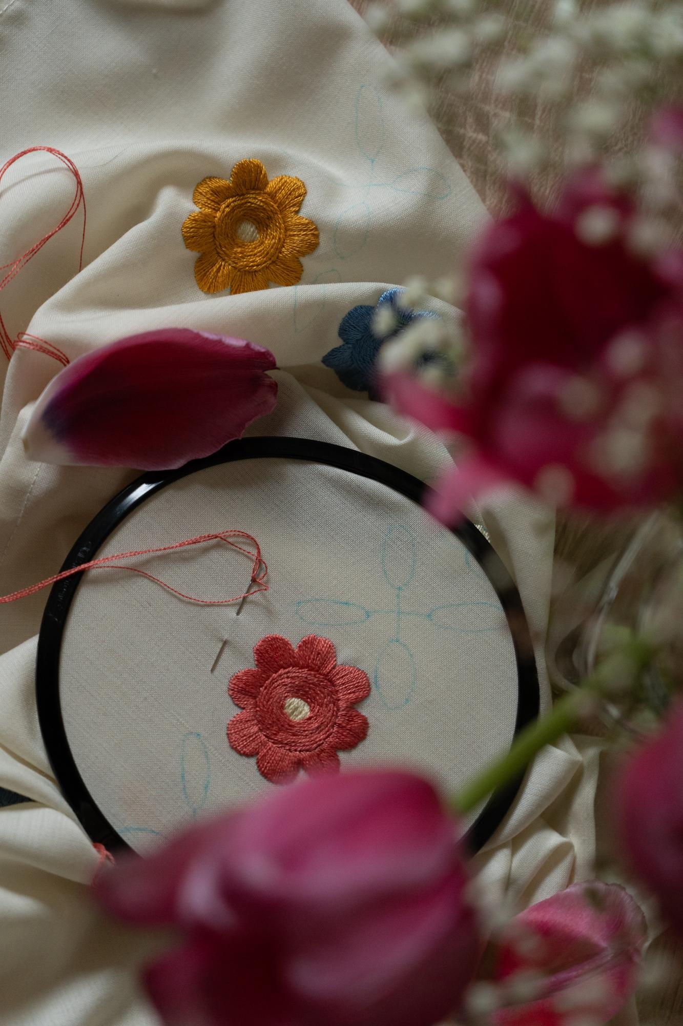 Artisan embroiderer stitching floral motif on linen